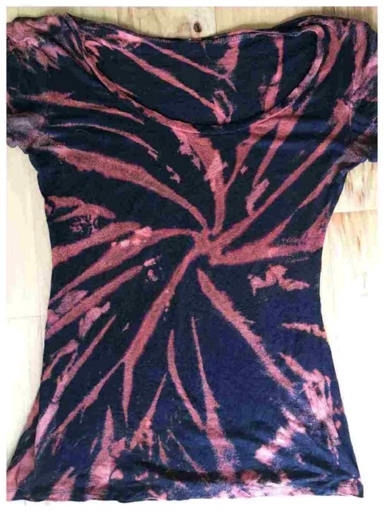 This t-shirt is made by first tie dying the fabric in the desired pattern, then using bleach to remove the color from the tied sections of the fabric.