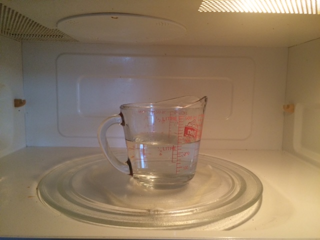 To boil water in a microwave, it should be placed in a microwave-safe container and heated on high for two to three minutes.